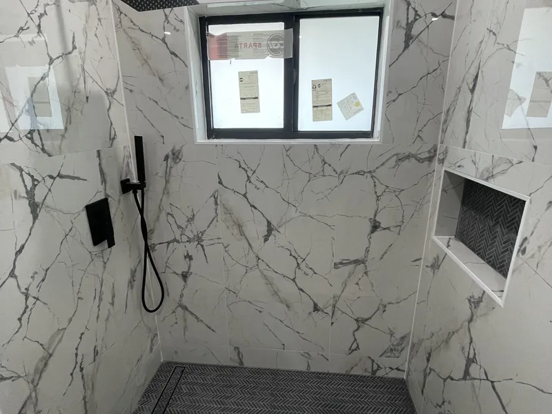 After: the same fourplex bathroom renovated with a marble walk-in shower